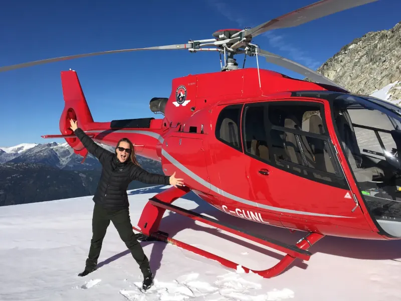 Isabell standing atop a mountain in front of a helicopter