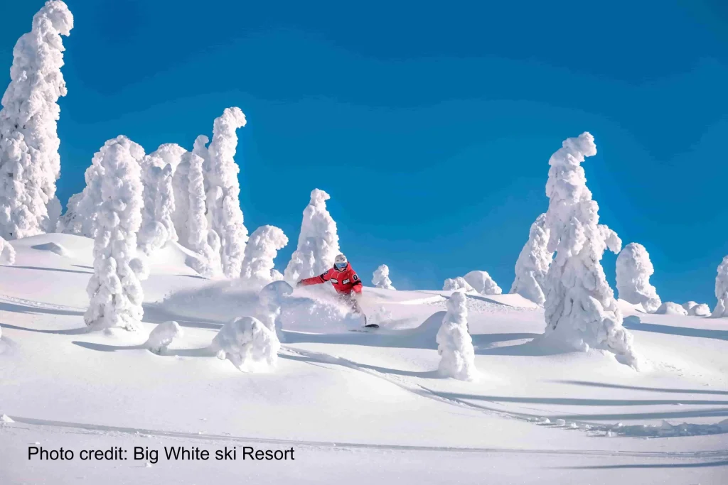 Big White 4 snowboarder in deep powder on a sunnyd at Big White Ski Resort