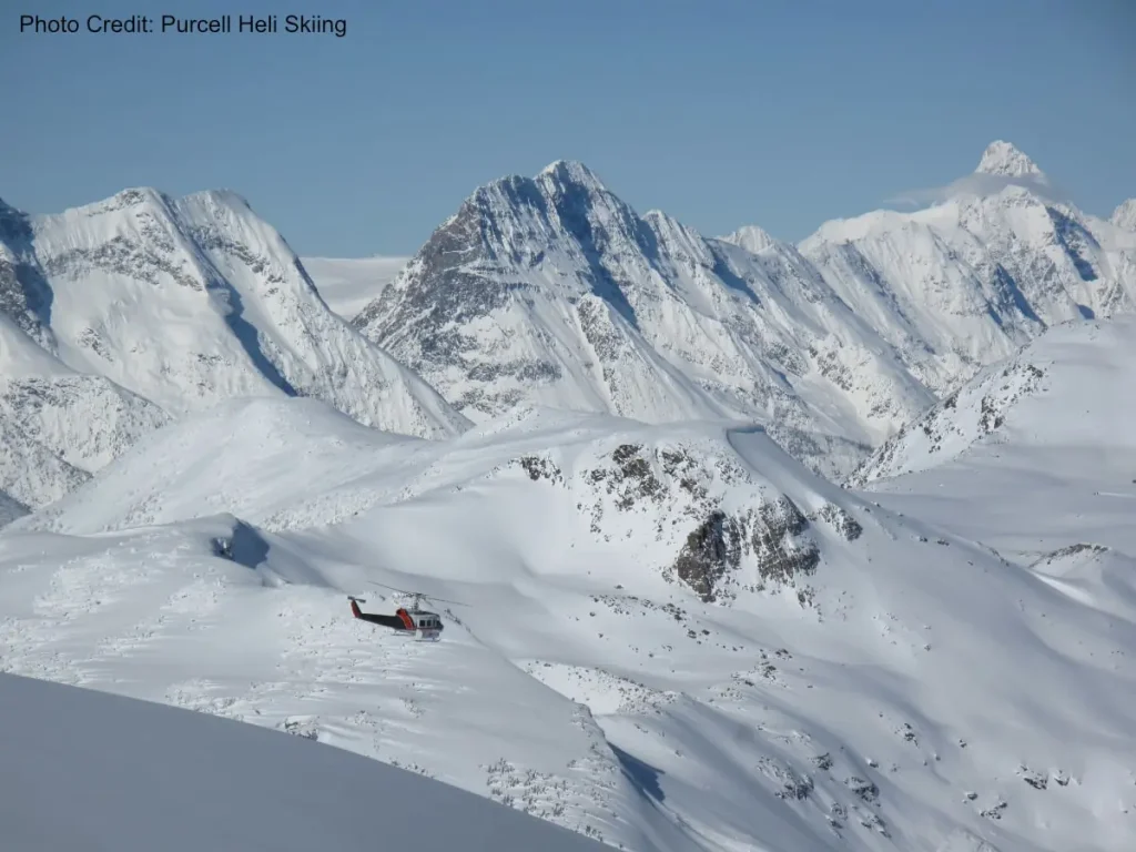Kicking Horse Heliski 2 helicopter flying over snowy peaks near Kicking Horse