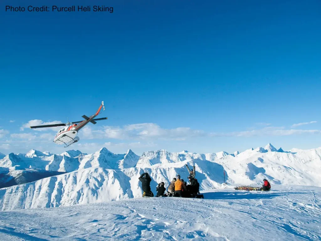 Kicking Horse Heliski 4 helicopter taking off after dropping skiers atop a peak near Kicking Horse resort