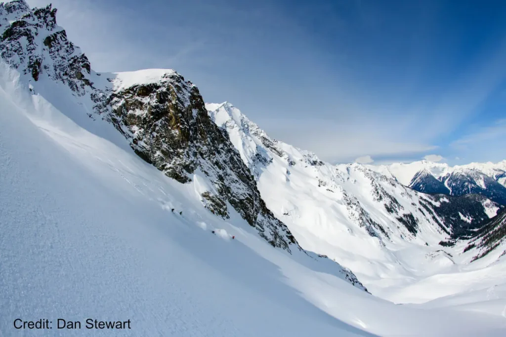 revelstoke-heliski 4 skiers descending steep powder in Revelstoke