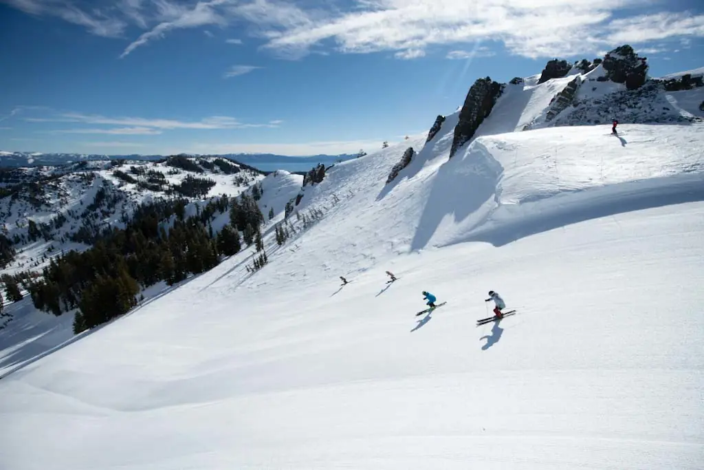 Palisades 2 skiers descending a groomed run on a sunny day in Palisades Tahoe, California