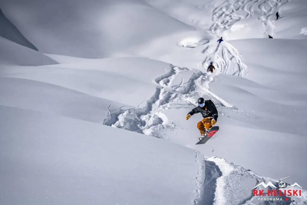 2025-03-22-RK-Mat-Loyola-323 snowboarder catching air and fresh track with RK Heli Ski