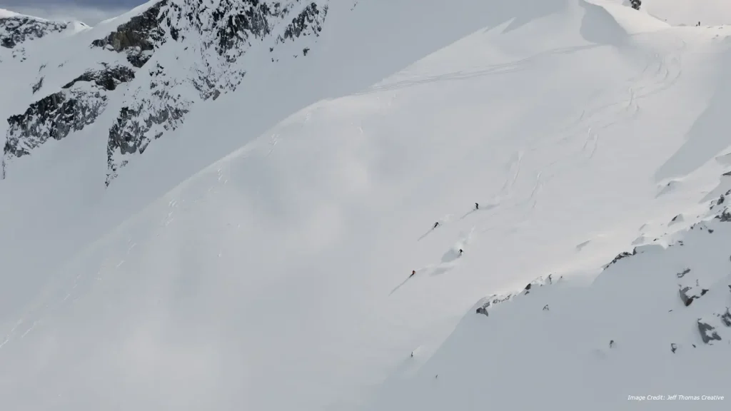 heli skiers getting fresh tracks in steep terrain