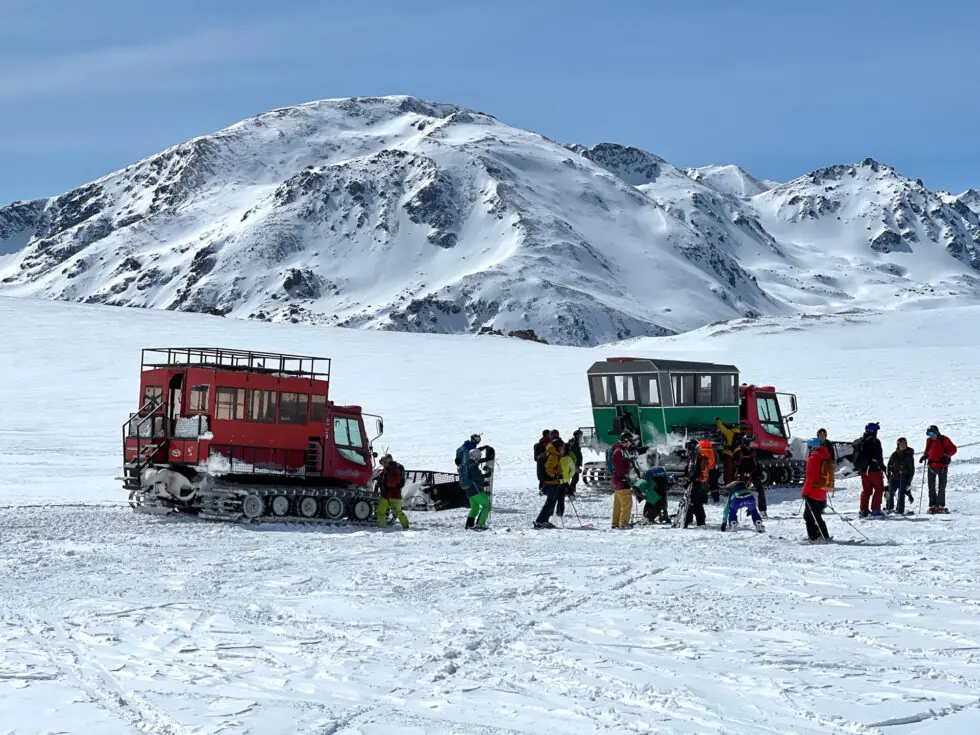 group of cat skiers and two cats on a snowy plateau 