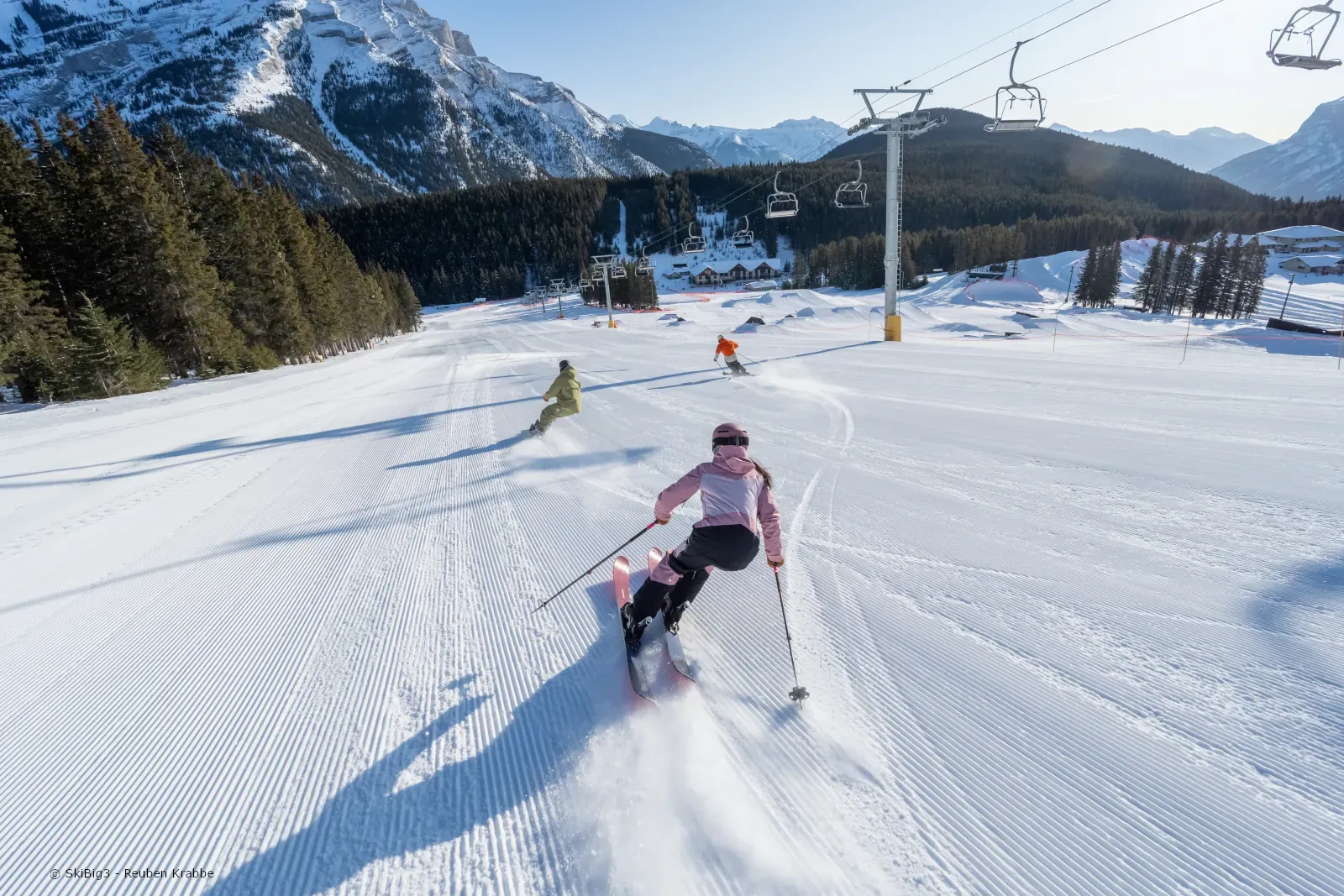 Skiers descending a groomed run at Banff, Norquay